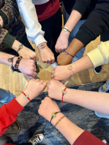 People putting their fists together in a circle to show off the word bracelets they are wearing.